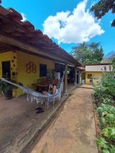 a man laying in a hammock outside a house at Recanto das Aves in Botumirim