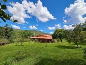 a building with a red roof in a field at Recanto das Aves in Botumirim