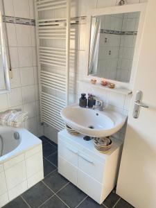 a white bathroom with a sink and a tub at Gemütliche Wohnung mit Berg- und Waldblick in Balingen
