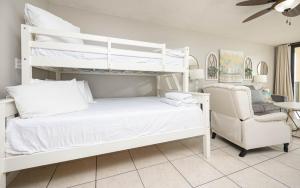 a bedroom with two bunk beds and a chair at Phoenix East II 2092 in Orange Beach