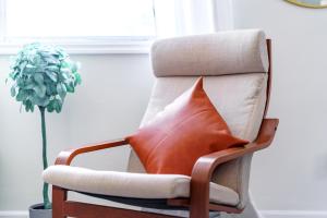 een stoel met een kussen in een kamer met een plant bij Jungle House Columbus Short North Downtown Free Parking - Steps to Convention Center & Nationwide Arena - 1BR Luxury Home - Sleeps 6 - Over 5,800 Five Star Stays in Columbus