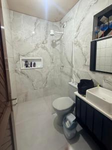 een witte badkamer met een toilet en een wastafel bij Vista Mar em PIÚMA in Itapitanga