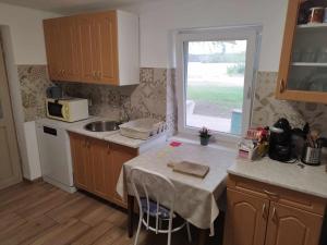 a kitchen with a table and a sink and a window at Napfény Tanya in Tázlár