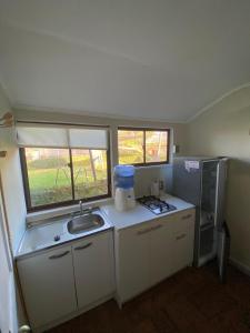 a small kitchen with a sink and two windows at Rancho Carmelitas Cabañas Familiares en Pullally, comuna Papudo in Quinquimo +92 photos