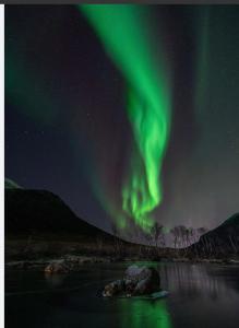 un'immagine dell'aurora nel cielo sopra un fiume di Kroken3 the apartment a Gravdal