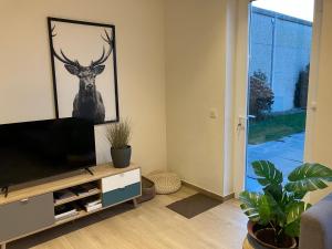 een woonkamer met een televisie en een schilderij van een hert bij vakantiewoning Het Boomkwekerijhuis in Zonnebeke
