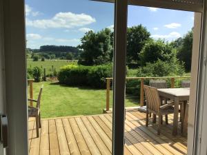 a sliding glass door to a deck with a table and chairs at Le Pré en Bulles in Chiny