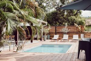 a swimming pool with chairs and a table and an umbrella at Villa Massy in Rivière-Salée