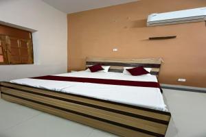 a bedroom with a large bed with white sheets and red pillows at Divine Blessings Banquet and Hotel in Prayagraj