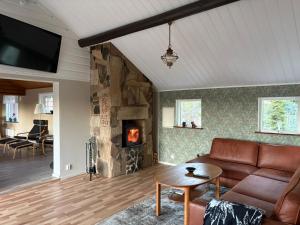 a living room with a couch and a fireplace at Åker Lilläng Solviken in Skillingaryd