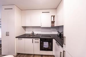 una cucina con mobili bianchi e un lavandino di The R Apartment Farnsberg a Basilea