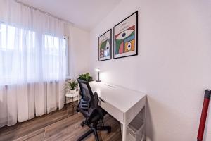 una scrivania bianca con sedia in una stanza con finestra di The R Apartment Farnsberg a Basilea
