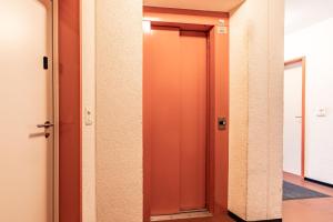 un corridoio con una porta arancione in un edificio di The R Apartment Farnsberg a Basilea