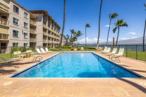 a swimming pool with chairs and a building at Maalaea Kai Resort 213 in Wailuku