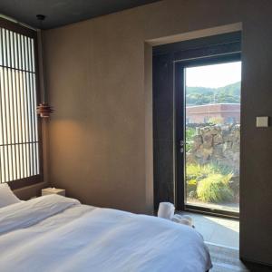 a bedroom with a bed and a large window at 제주 감성숙소 스테이보스케 in Jeju