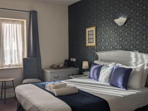 a bedroom with a large bed and a chair at Hitchin Priory Inn in Hitchin