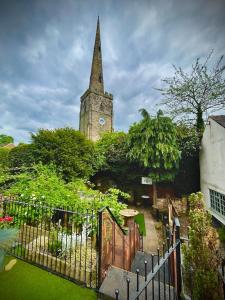 un campanile di una chiesa con una torre dell'orologio dietro una recinzione di Birdellas the eleganant one a Castle Donington