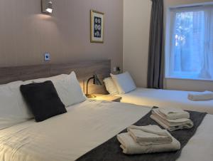 a hotel room with two beds with towels on them at Hitchin Priory Inn in Hitchin +7 photos