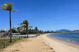 a beach with palm trees and surfboards on it at Flat Praia Comfort Camburi in Vitória