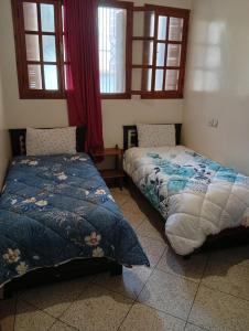 two beds sitting in a room with windows at Chez-soi in Meknès