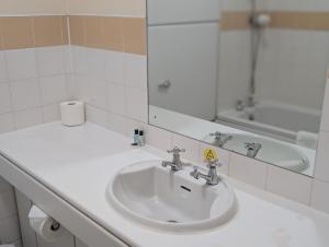 a bathroom with a white sink and a mirror at Hitchin Priory Inn in Hitchin