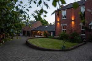 een bakstenen huis met een binnenplaats ervoor bij Garden Cottage at Old Post Office in Bardon Mill