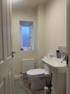 a white bathroom with a toilet and a sink at The Calm Space Room in Balderton +5 photos