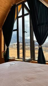 a bedroom with a bed and a large window at Cottage Cozy Yard in Kazbegi