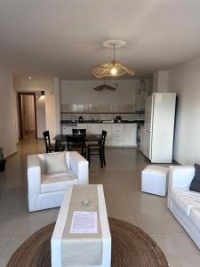 a living room with white furniture and a kitchen at Depto centro in Villa Carlos Paz