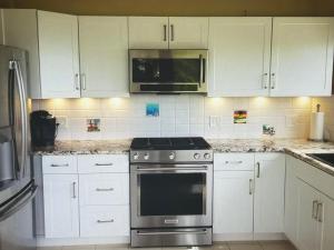 a kitchen with white cabinets and a stainless steel oven at Superbe Zions Hill Views in Sion Farm