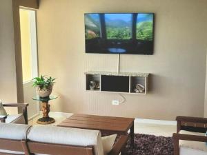 a living room with a couch and a tv on the wall at Superbe Zions Hill Views in Sion Farm