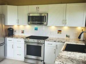 a kitchen with white cabinets and a stove and a microwave at Superbe Zions Hill Views in Sion Farm +5 photos