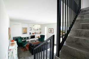 een woonkamer met een trap en groene stoelen bij Villa With Views Over Ombrone Valley in Campagnatico +15 foto's