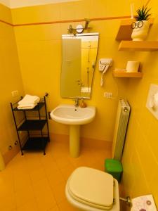 ein gelbes Badezimmer mit Toilette und Waschbecken in der Unterkunft Amici Miei Rooms in Cremona
