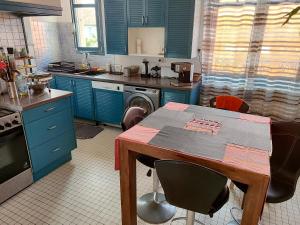 a kitchen with blue cabinets and a table with chairs at Appartement avec Terrasse à Beaurivage in Biarritz