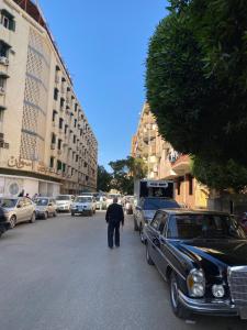 a man walking down a street next to a car at Jme Bunks Hostel in Aswān