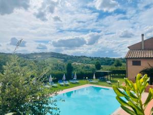 a swimming pool with chairs and a view of the mountains at Borgo degli Orti in Montaione
