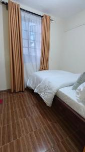 a bedroom with two beds and a window at Coral Homes in Juja