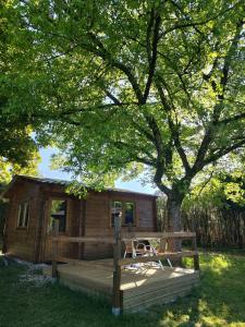 a log cabin under a tree with a wooden deck at Camping Les Rochelles in Prunay-Cassereau +20 photos