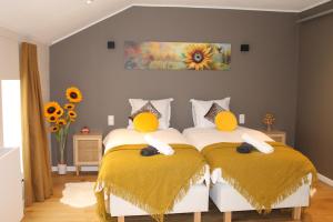 una camera con 2 letti con cuscini gialli di Le Relais de Lou maison d'hôtes 