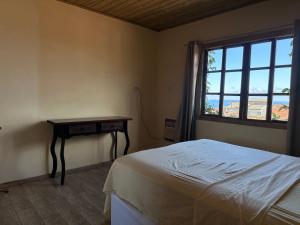 a bedroom with a bed and a table and a window at Casa Vila Nova Alvorada in Imbituba