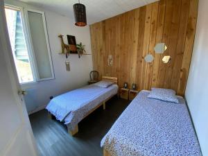 two beds in a room with wooden walls at Maison idéale pour visiter Bordeaux in Ambarès-et-Lagrave