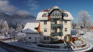 a large white house with snow on the ground at Ferienwohnungen Ammerwinkel in Oberammergau