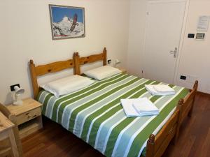 een slaapkamer met een bed met groene en witte gestreepte lakens bij Affittacamere Penasa in Rabbi