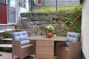 a table with two chairs and a vase of flowers at Ferienwohnung Urlaubszeit in Illingen