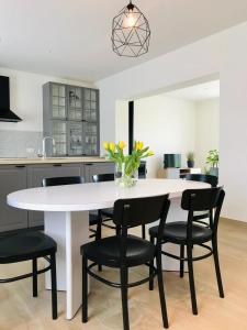 een keuken met een witte tafel en zwarte stoelen bij vakantiewoning Het Boomkwekerijhuis in Zonnebeke