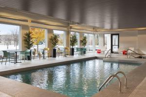 a swimming pool with tables and chairs in a building at Home2 Suites By Hilton Vaughan Toronto On in Vaughan