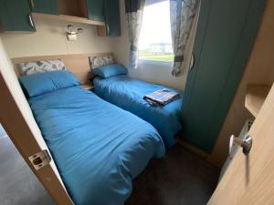 two beds in a small room with a window at No 56 Headiton Caravan Park in Banff