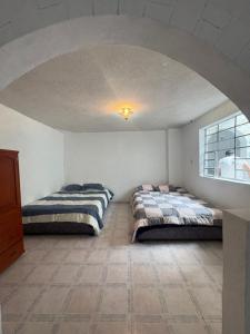 two beds in a room with an archway at Hostal Los Robles in Pasto