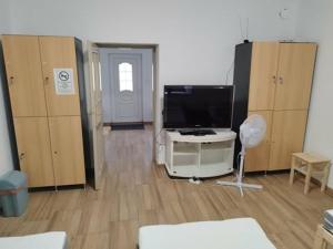 a room with a tv and a room with wooden cabinets at Napfény Tanya in Tázlár